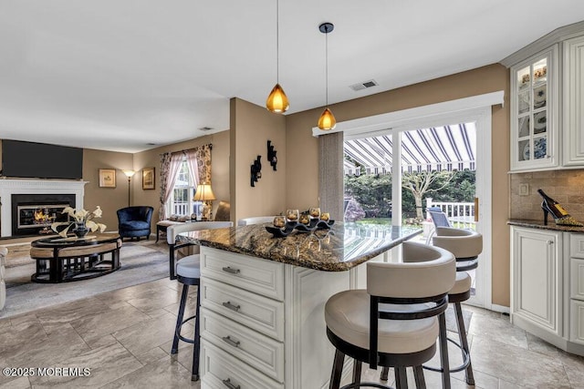 32 Tilton Rd, Brick, NJ 08723 - kitchen with a breakfast bar area, glass insert cabinets, open floor plan, a glass covered fireplace, and dark stone countertops