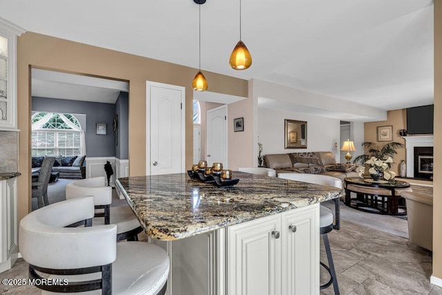 32 Tilton Rd, Brick, NJ 08723 - kitchen with a breakfast bar, open floor plan, dark stone countertops, decorative light fixtures, and a glass covered fireplace