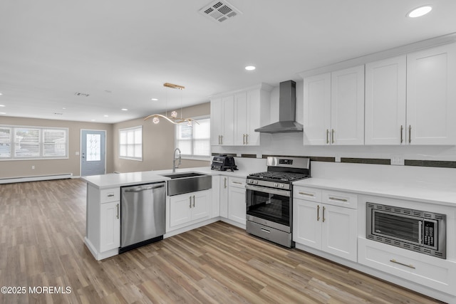 171 Biabou Dr, Toms River, NJ 08757 - kitchen with wall chimney exhaust hood, stainless steel appliances, baseboard heating, a peninsula, and light countertops