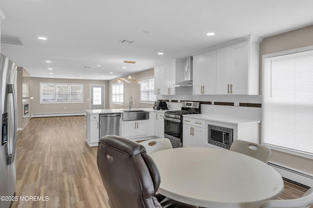 171 Biabou Dr, Toms River, NJ 08757 - kitchen with appliances with stainless steel finishes, wall chimney range hood, a peninsula, a warm lit fireplace, and recessed lighting