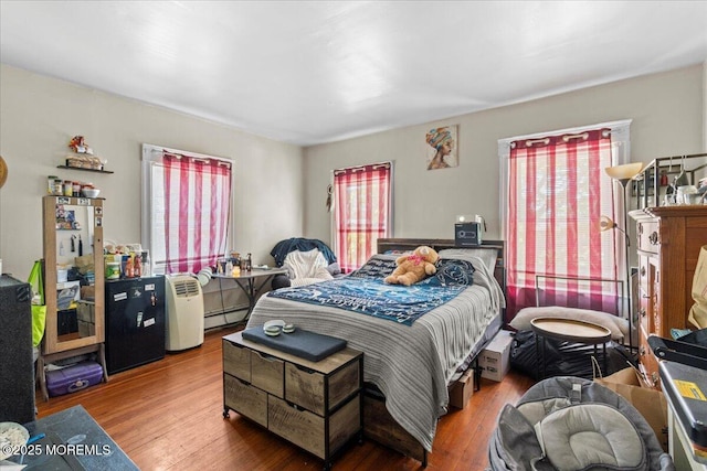 1015 Mattison Ave, Asbury Park, NJ 07712 - bedroom featuring multiple windows, wood finished floors, and a baseboard heating unit