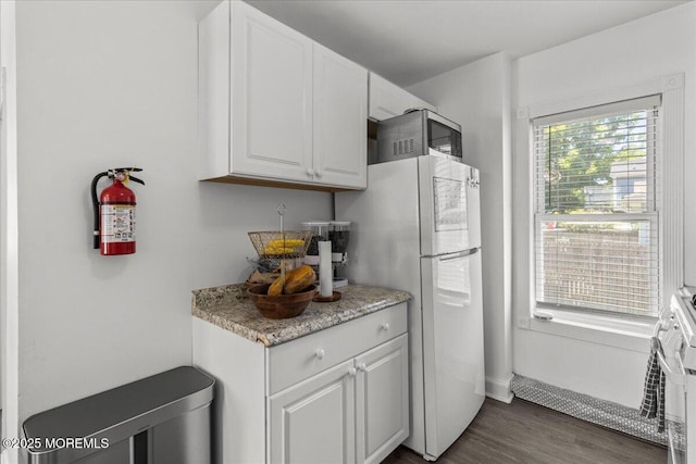 1015 Mattison Ave, Asbury Park, NJ 07712 - kitchen featuring stainless steel microwave, freestanding refrigerator, white cabinetry, dark wood-style floors, and range