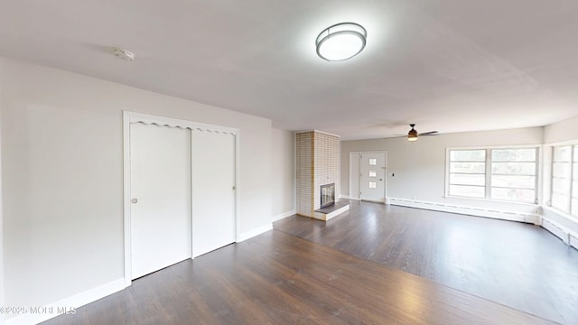 574 Main St, Sayreville, NJ 08872 - unfurnished living room with ceiling fan, dark wood-style floors, a baseboard heating unit, and a brick fireplace