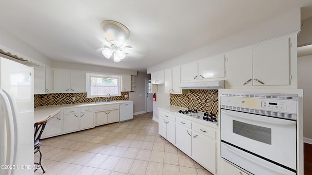 574 Main St, Sayreville, NJ 08872 - kitchen with white appliances, under cabinet range hood, tasteful backsplash, light countertops, and white cabinets