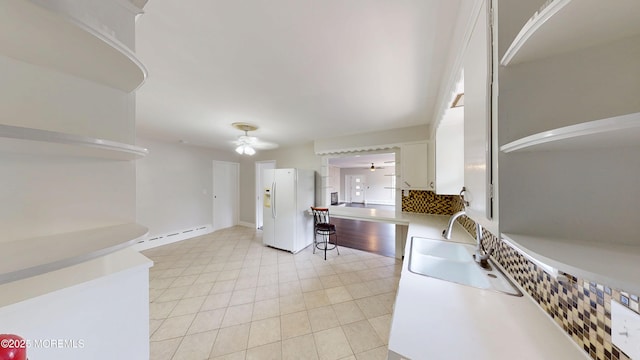 574 Main St, Sayreville, NJ 08872 - kitchen with white refrigerator with ice dispenser, a ceiling fan, baseboard heating, white cabinets, and light countertops