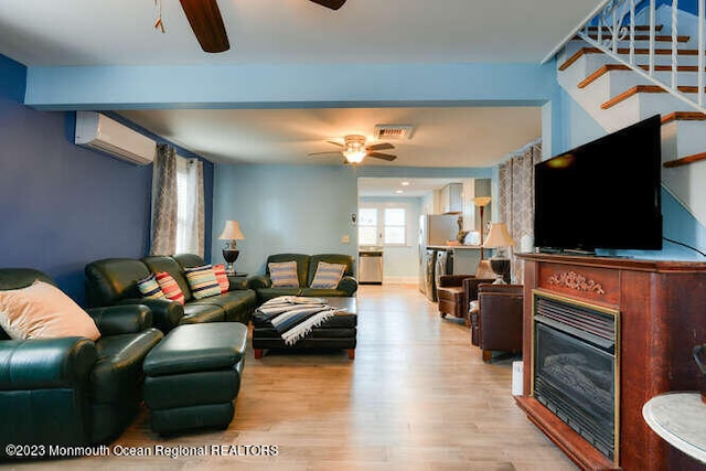 63 Asbury Ave, Ocean Grove, NJ 07756 - living room featuring ceiling fan, a wall unit AC, wood finished floors, a glass covered fireplace, and stairway
