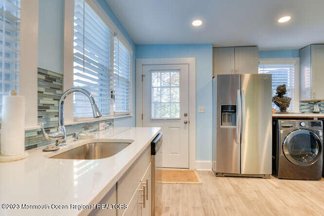 63 Asbury Ave, Ocean Grove, NJ 07756 - kitchen featuring washer / dryer, stainless steel appliances, light wood finished floors, tasteful backsplash, and light countertops