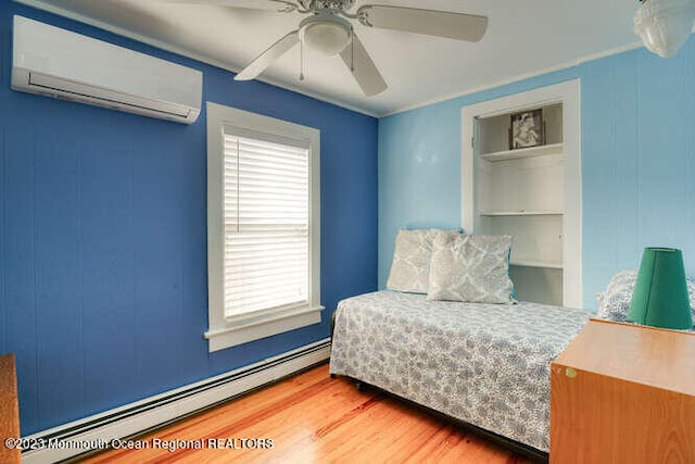 63 Asbury Ave, Ocean Grove, NJ 07756 - bedroom featuring baseboard heating, an AC wall unit, multiple windows, and wood finished floors