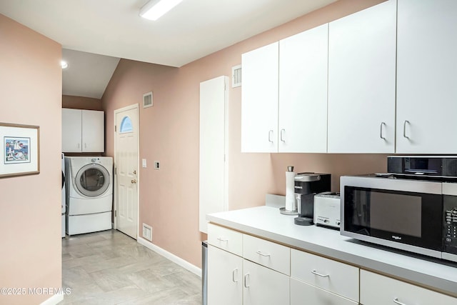 7 Jayhawk Way, Holmdel, NJ 07733 - kitchen with stainless steel microwave, washer / dryer, light countertops, vaulted ceiling, and white cabinetry