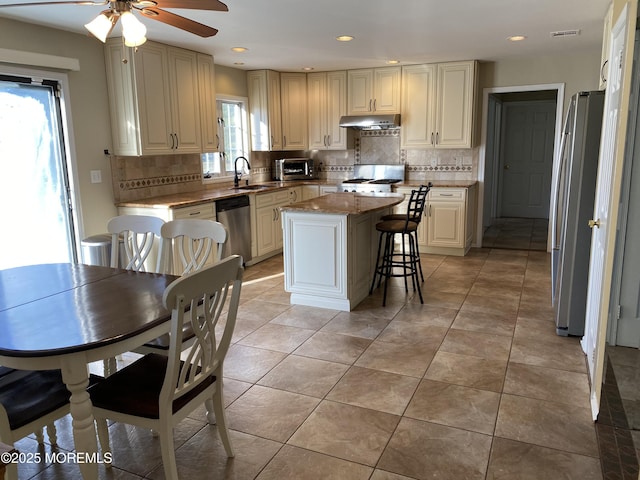 7 Erte Pl, Marlboro, NJ 07746 - kitchen with under cabinet range hood, stainless steel appliances, a ceiling fan, backsplash, and a kitchen island