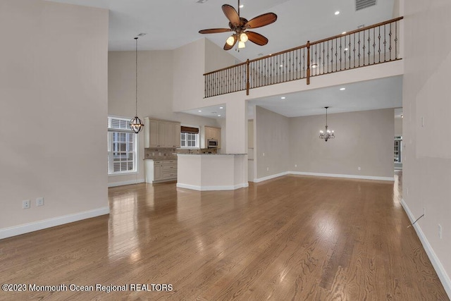 25 Merion Ln, Jackson, NJ 08527 - unfurnished living room with a chandelier, a ceiling fan, a towering ceiling, and wood finished floors