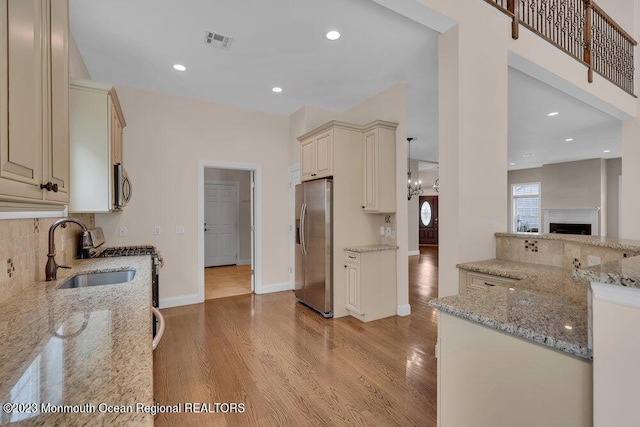 25 Merion Ln, Jackson, NJ 08527 - kitchen with stainless steel appliances, cream cabinets, tasteful backsplash, light wood finished floors, and light stone countertops