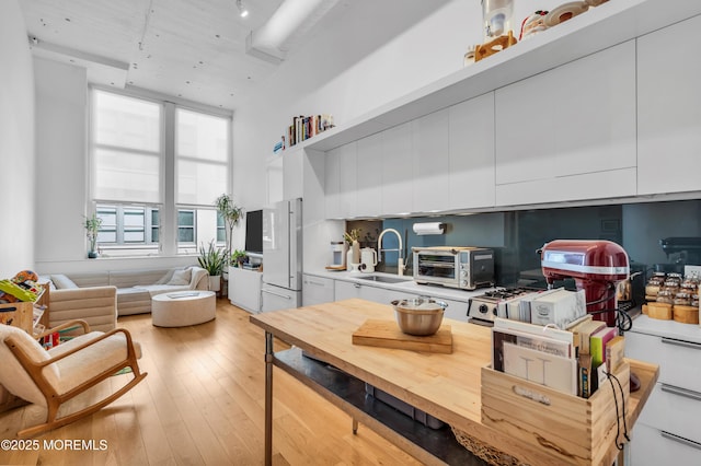 50 Dey St Unit 434, Jersey City, NJ 07306 - kitchen featuring freestanding refrigerator, white cabinets, modern cabinets, light wood finished floors, and a high ceiling
