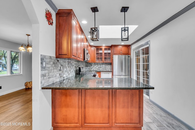 215 Sunset Ln, Howell, NJ 07731 - kitchen with stainless steel appliances, backsplash, dark stone counters, glass insert cabinets, and light wood finished floors