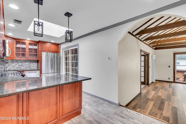 215 Sunset Ln, Howell, NJ 07731 - kitchen featuring stainless steel appliances, tasteful backsplash, light wood-style floors, arched walkways, and dark stone counters