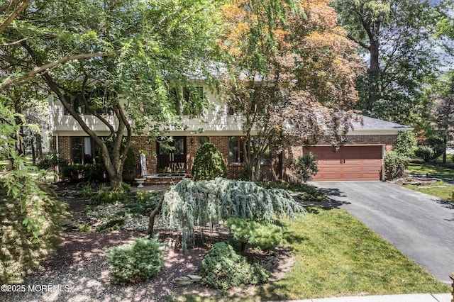 27 Darby Rd, East Brunswick, NJ 08816 - view of property hidden behind natural elements featuring brick siding, driveway, and an attached garage