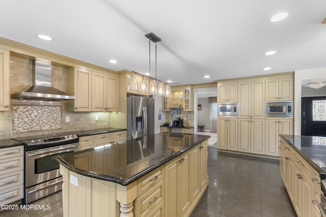 136 Sunset Rd, Lakewood, NJ 08701 - kitchen featuring wall chimney exhaust hood, appliances with stainless steel finishes, cream cabinetry, tasteful backsplash, and a kitchen island