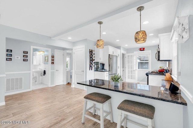 1 Cedar Ave, Rumson, NJ 07760 - kitchen with appliances with stainless steel finishes, a peninsula, white cabinetry, light wood finished floors, and dark stone countertops