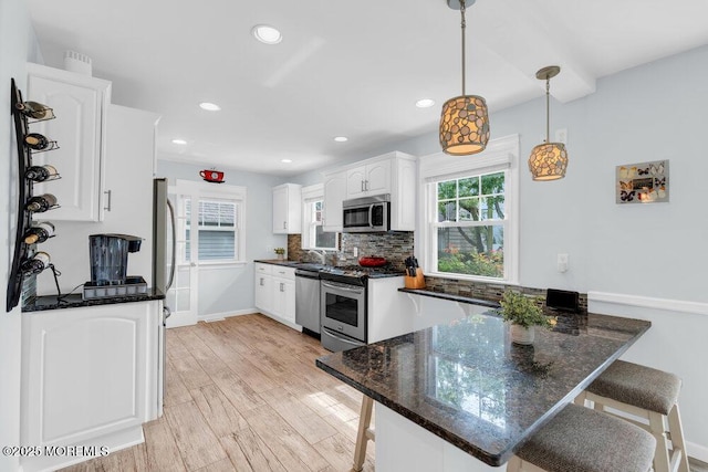 1 Cedar Ave, Rumson, NJ 07760 - kitchen with appliances with stainless steel finishes, a breakfast bar area, white cabinets, a peninsula, and plenty of natural light