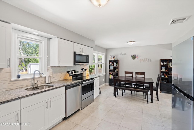 482 Radovan Ave, Bayville, NJ 08721 - kitchen featuring appliances with stainless steel finishes, tasteful backsplash, light tile patterned floors, stone counters, and white cabinetry