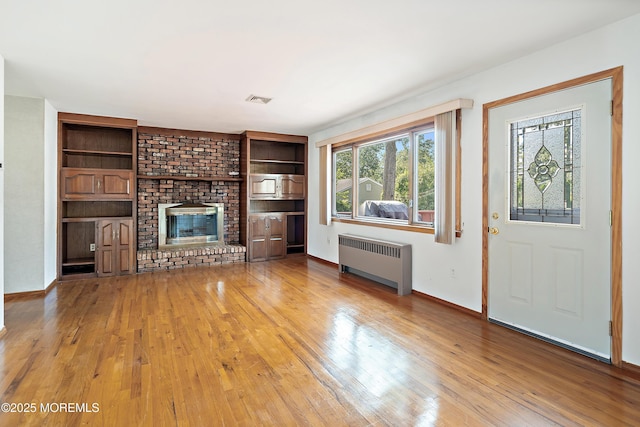 2238 Emerald Park Dr, Forked River, NJ 08731 - unfurnished living room with radiator heating unit, plenty of natural light, wood finished floors, and a brick fireplace