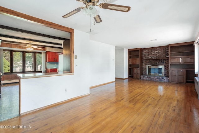 2238 Emerald Park Dr, Forked River, NJ 08731 - unfurnished living room featuring a ceiling fan, wood finished floors, a baseboard heating unit, a fireplace, and built in shelves