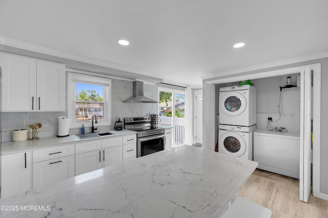 8 Navarra Dr, Brick, NJ 08723 - kitchen with stainless steel range with electric cooktop, wall chimney exhaust hood, stacked washer / dryer, crown molding, and white cabinetry