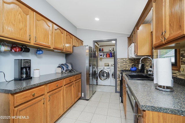 14 Cedar Ct, Manalapan, NJ 07726 - kitchen featuring washing machine and dryer, lofted ceiling, stainless steel appliances, light tile patterned flooring, and dark countertops