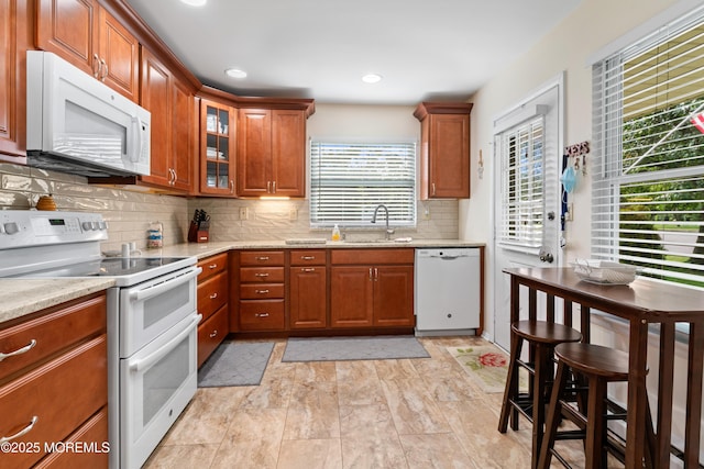 799B Westminster Ct Unit B, Manchester, NJ 08759 - kitchen with white appliances, brown cabinetry, tasteful backsplash, glass insert cabinets, and light stone countertops