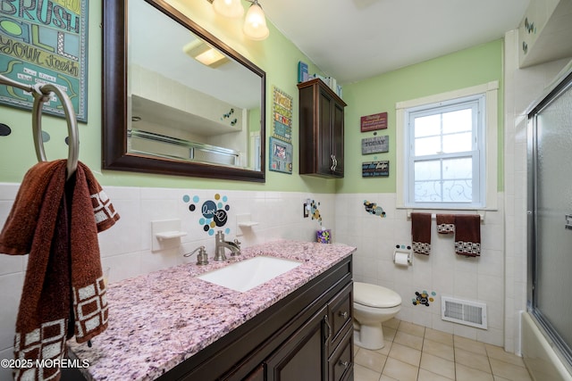 9 Partridge Ave, Freehold, NJ 07728 - full bathroom featuring vanity, tile patterned floors, tile walls, a wainscoted wall, and bath / shower combo with glass door