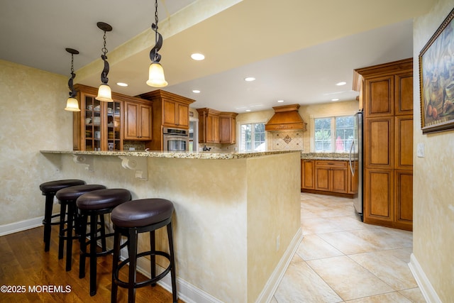 9 Partridge Ave, Freehold, NJ 07728 - kitchen with appliances with stainless steel finishes, premium range hood, brown cabinetry, light stone countertops, and recessed lighting
