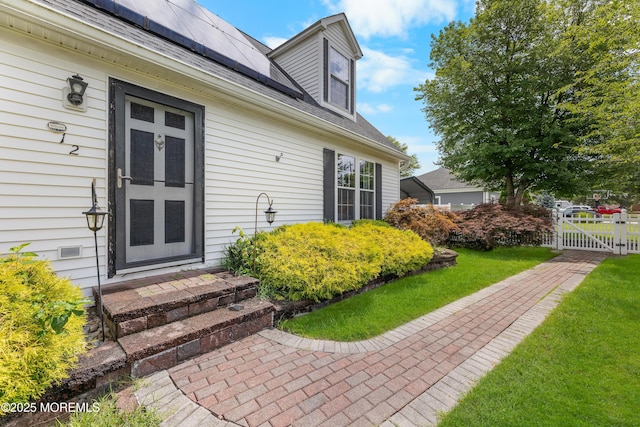 12 Liberty St, Old Bridge, NJ 08857 - property entrance with a gate, roof mounted solar panels, a yard, and a shingled roof