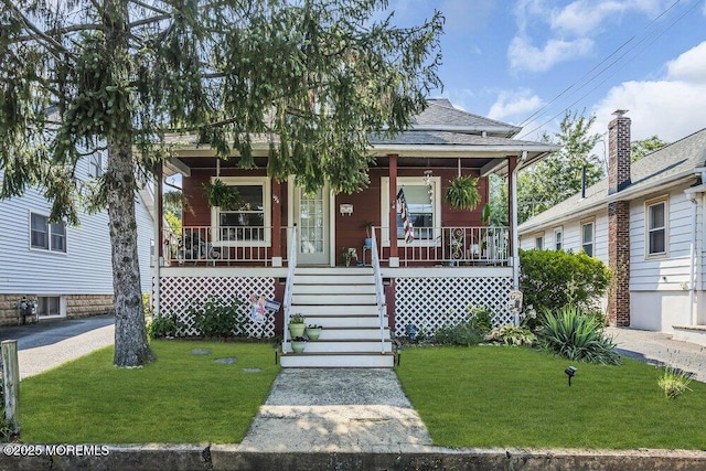 194 Washington St, Keyport, NJ 07735 - shotgun-style home with covered porch, a front yard, and a shingled roof