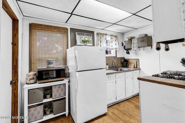 194 Washington St, Keyport, NJ 07735 - kitchen featuring freestanding refrigerator, stainless steel microwave, white cabinets, a paneled ceiling, and light wood-style flooring