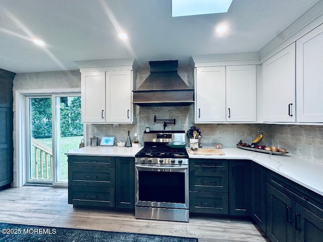 412 Steuben Ave, Forked River, NJ 08731 - kitchen featuring stainless steel range with gas cooktop, premium range hood, white cabinets, backsplash, and a skylight