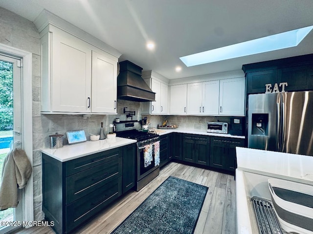 412 Steuben Ave, Forked River, NJ 08731 - kitchen with stainless steel appliances, custom exhaust hood, a skylight, light countertops, and light wood-type flooring