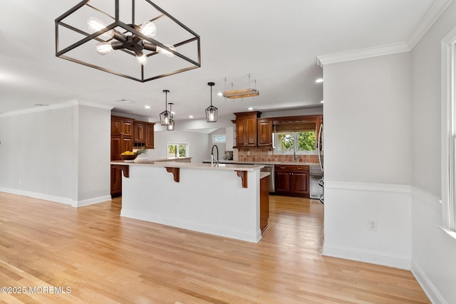 6 Frances Ct, Red Bank, NJ 07701 - kitchen featuring a breakfast bar area, light countertops, light wood-style floors, a center island with sink, and decorative backsplash