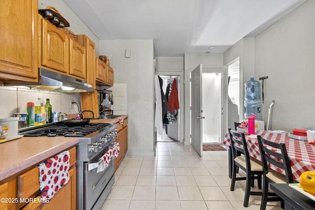 612 Grier Ave, Elizabeth, NJ 07202 - kitchen featuring high end stainless steel range oven, light tile patterned floors, brown cabinets, under cabinet range hood, and light countertops