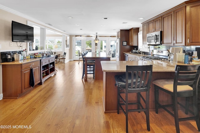 49 Farragut Dr, Brick, NJ 08723 - kitchen featuring stainless steel appliances, light stone counters, a kitchen breakfast bar, crown molding, and light wood-type flooring