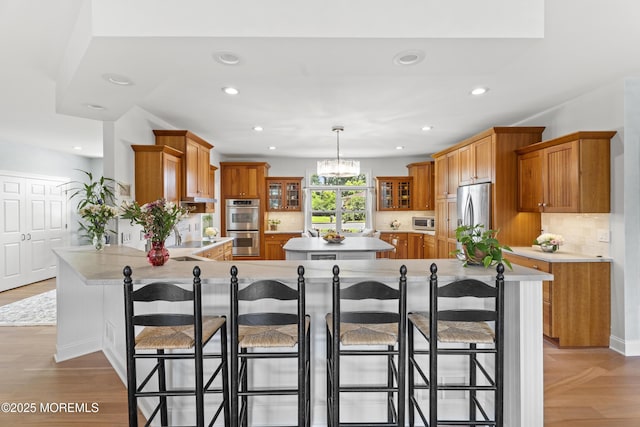 11 Sharon Dr, Ocean Twp, NJ 07712 - kitchen featuring appliances with stainless steel finishes, a peninsula, recessed lighting, brown cabinets, and glass insert cabinets