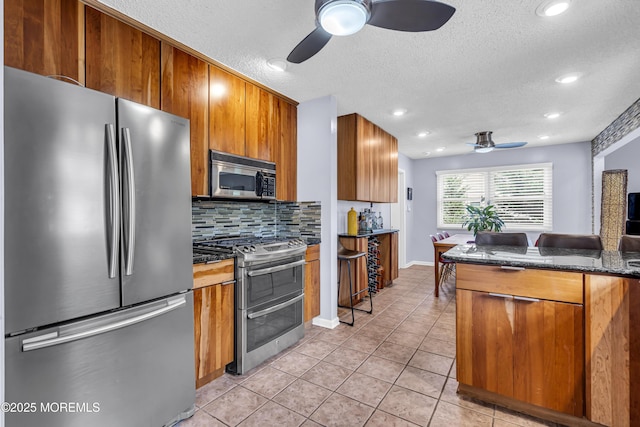 707 Cambridge Rd, Lanoka Harbor, NJ 08734 - kitchen featuring stainless steel appliances, a ceiling fan, brown cabinets, tasteful backsplash, and light tile patterned floors