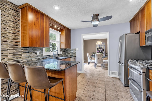 707 Cambridge Rd, Lanoka Harbor, NJ 08734 - kitchen featuring appliances with stainless steel finishes, ceiling fan, tasteful backsplash, a peninsula, and brown cabinets