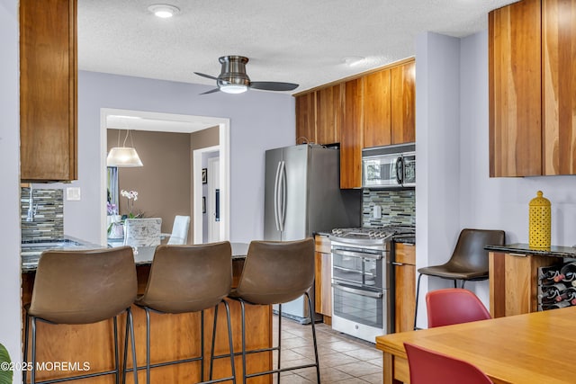 707 Cambridge Rd, Lanoka Harbor, NJ 08734 - kitchen featuring stainless steel appliances, brown cabinets, tasteful backsplash, ceiling fan, and light tile patterned floors