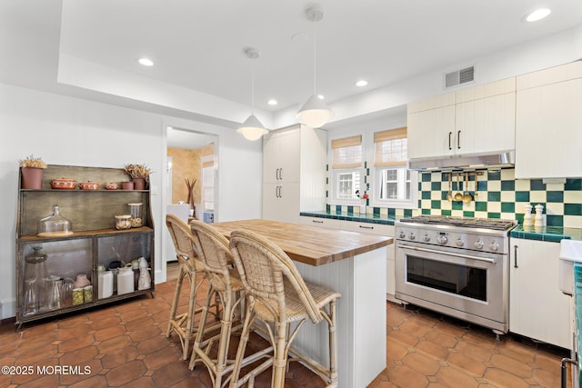 312 Lake Dr, Allenhurst, NJ 07711 - kitchen featuring high end stainless steel range oven, decorative backsplash, a breakfast bar area, butcher block countertops, and recessed lighting