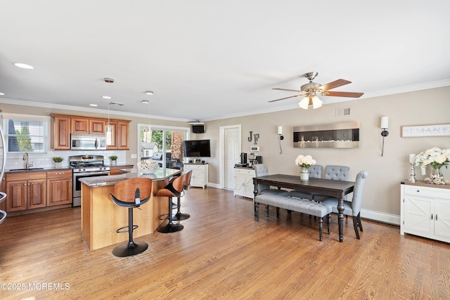 1020 Sarasota Dr, Forked River, NJ 08731 - kitchen featuring appliances with stainless steel finishes, a breakfast bar, brown cabinetry, a ceiling fan, and a center island