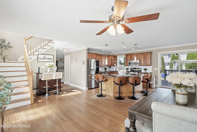 1020 Sarasota Dr, Forked River, NJ 08731 - kitchen with appliances with stainless steel finishes, a breakfast bar area, crown molding, light wood finished floors, and a kitchen island