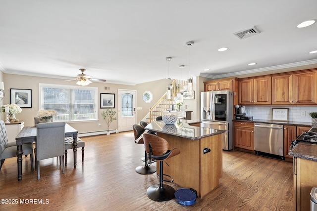 1020 Sarasota Dr, Forked River, NJ 08731 - kitchen featuring appliances with stainless steel finishes, a center island, brown cabinetry, crown molding, and a kitchen bar