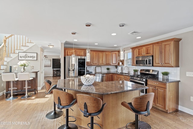 1020 Sarasota Dr, Forked River, NJ 08731 - kitchen with appliances with stainless steel finishes, brown cabinets, light wood-style floors, dark stone countertops, and ornamental molding