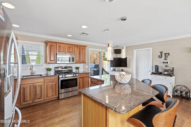 1020 Sarasota Dr, Forked River, NJ 08731 - kitchen featuring stainless steel appliances, a kitchen island, a breakfast bar, ornamental molding, and light wood-style floors