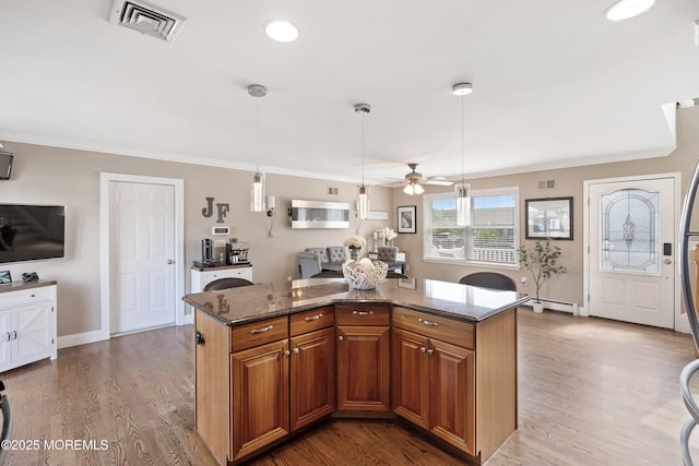1020 Sarasota Dr, Forked River, NJ 08731 - kitchen featuring a ceiling fan, dark stone counters, crown molding, brown cabinets, and a kitchen island